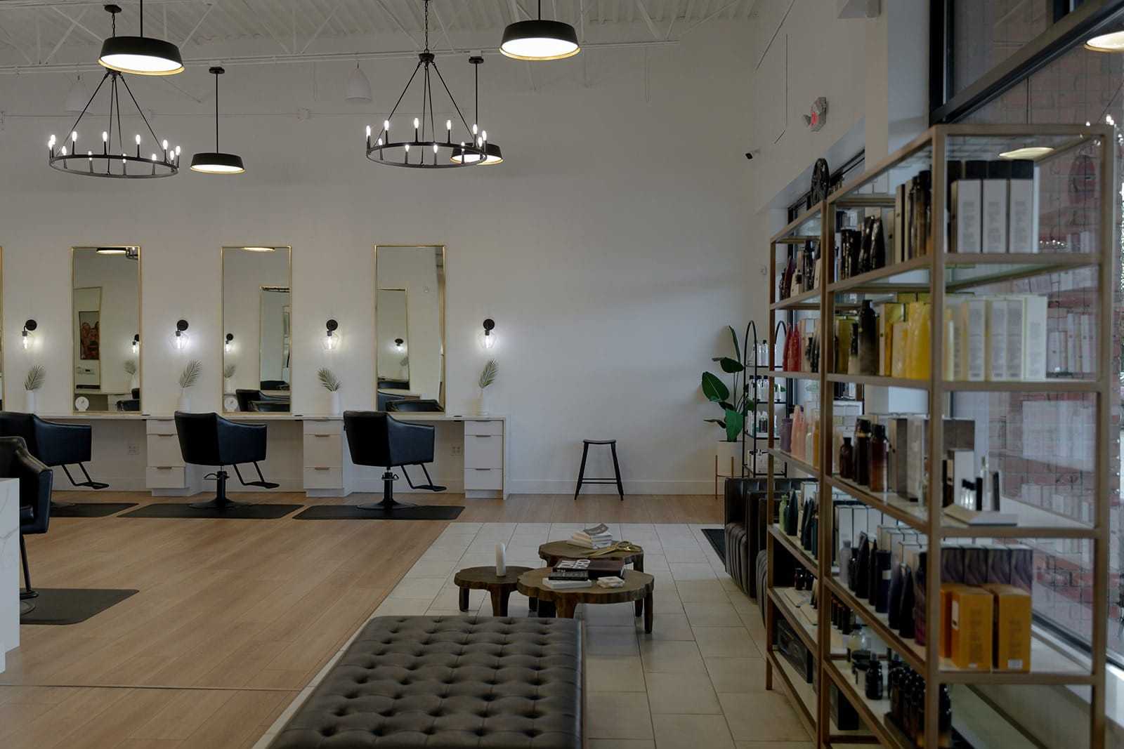 Modern hair salon interior with mirrors, chairs, and shelves of hair products.