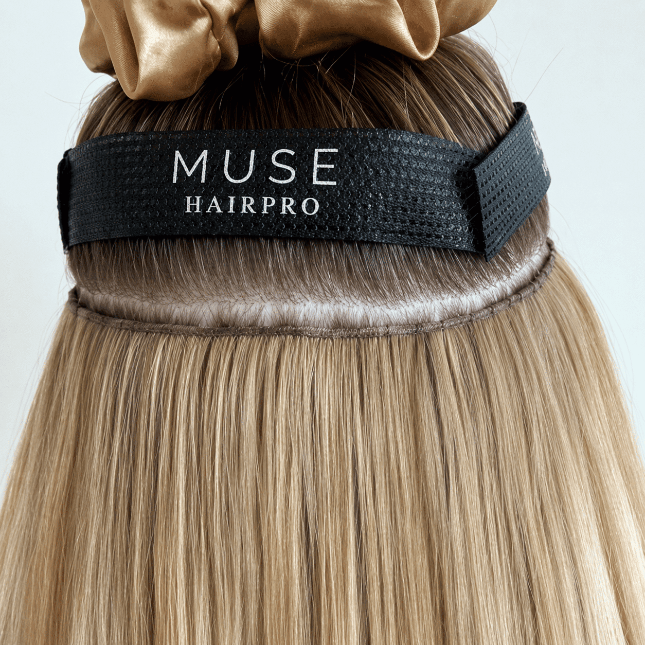 Hair extension secured with a MUSE HAIRPRO band on blonde hair with a brown scrunchie.