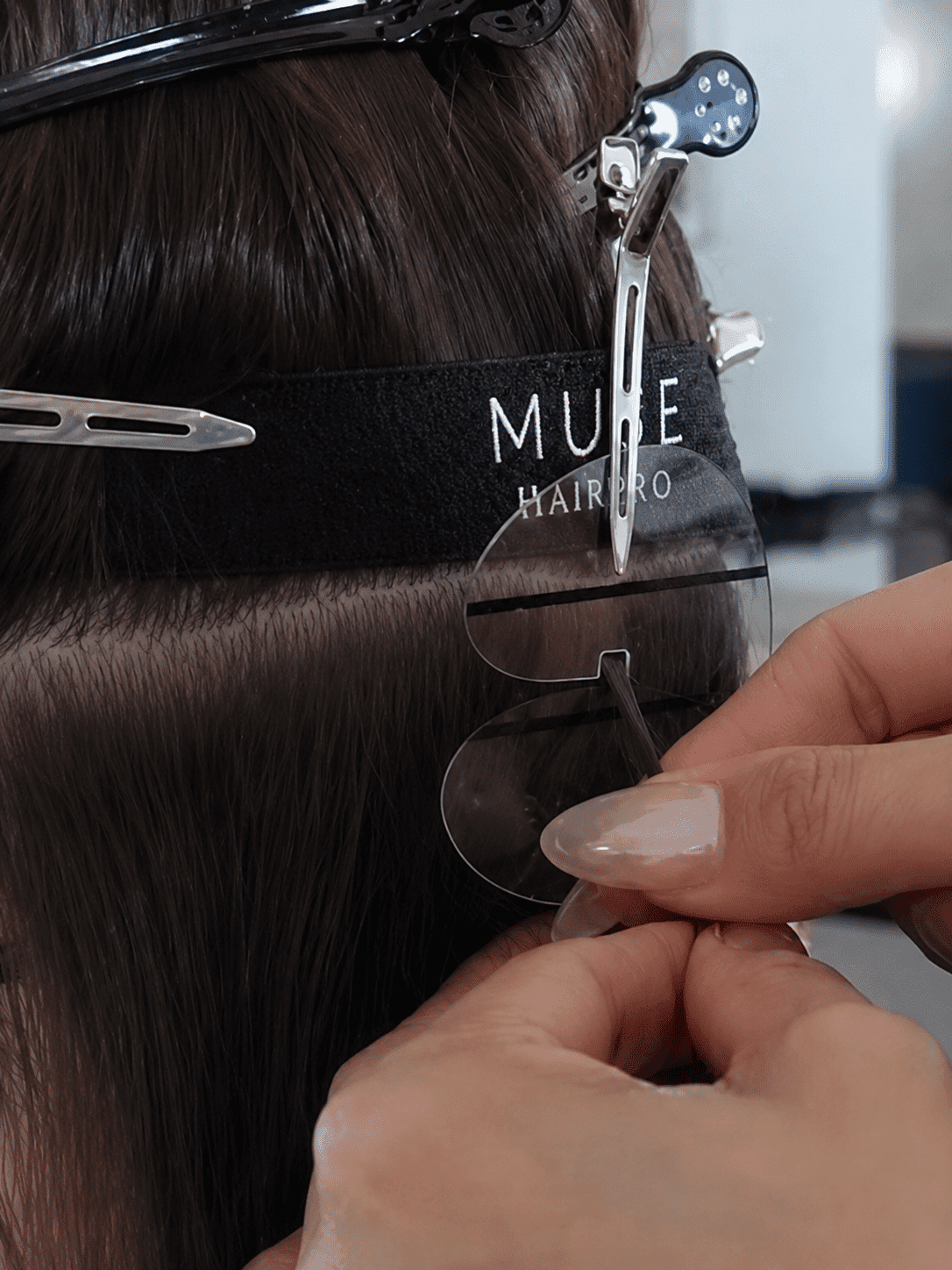 Hair extension being carefully applied with clips and transparent adhesive.